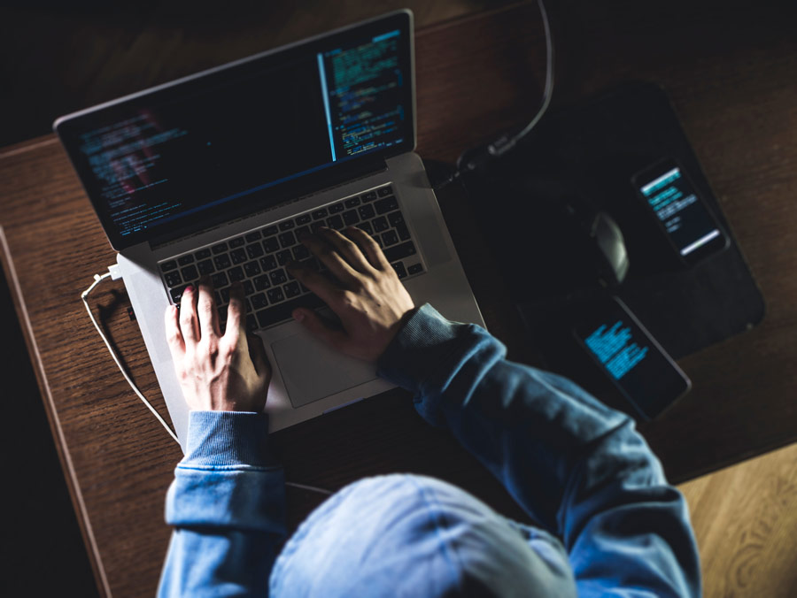 Hooded man using a laptop computer